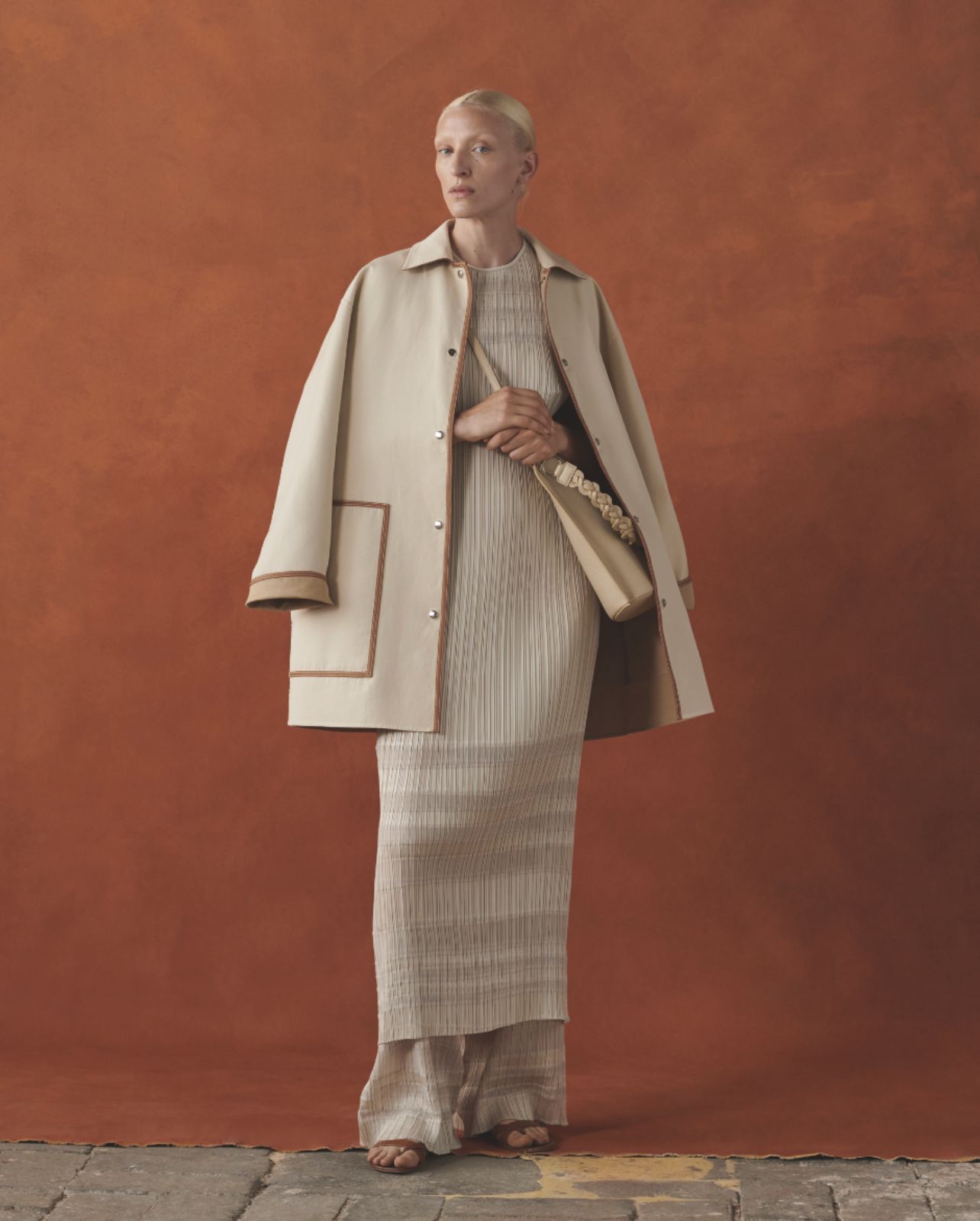 model poses in a cream colored dress and coat