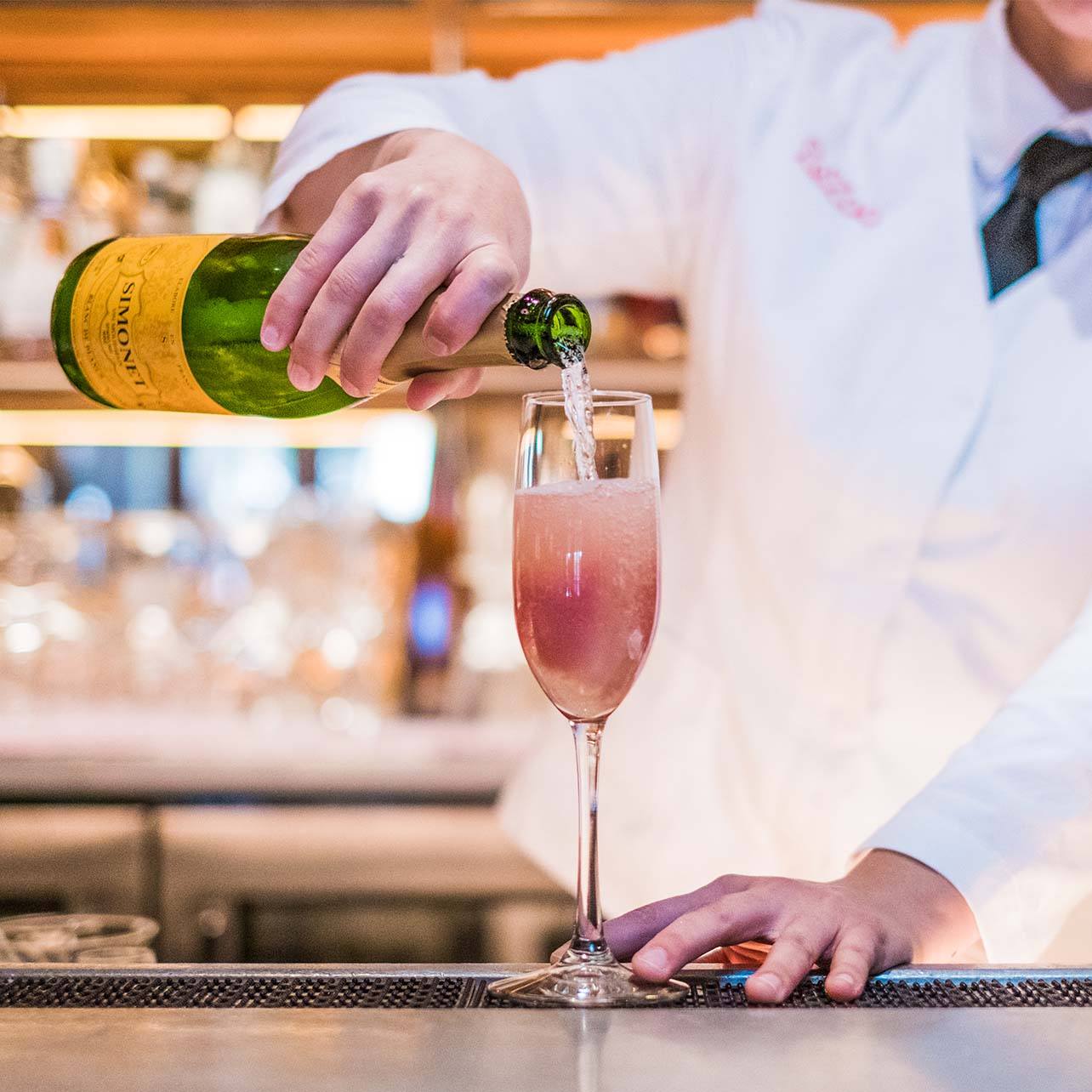 Bartender pouring champagne into a cocktail