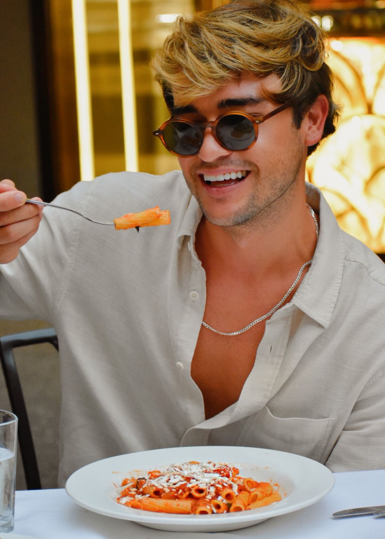 Sebastian Genta smiles while holding up a fork of pasta from Carpaccio