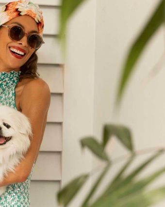 Model smiles while holding a small white dog