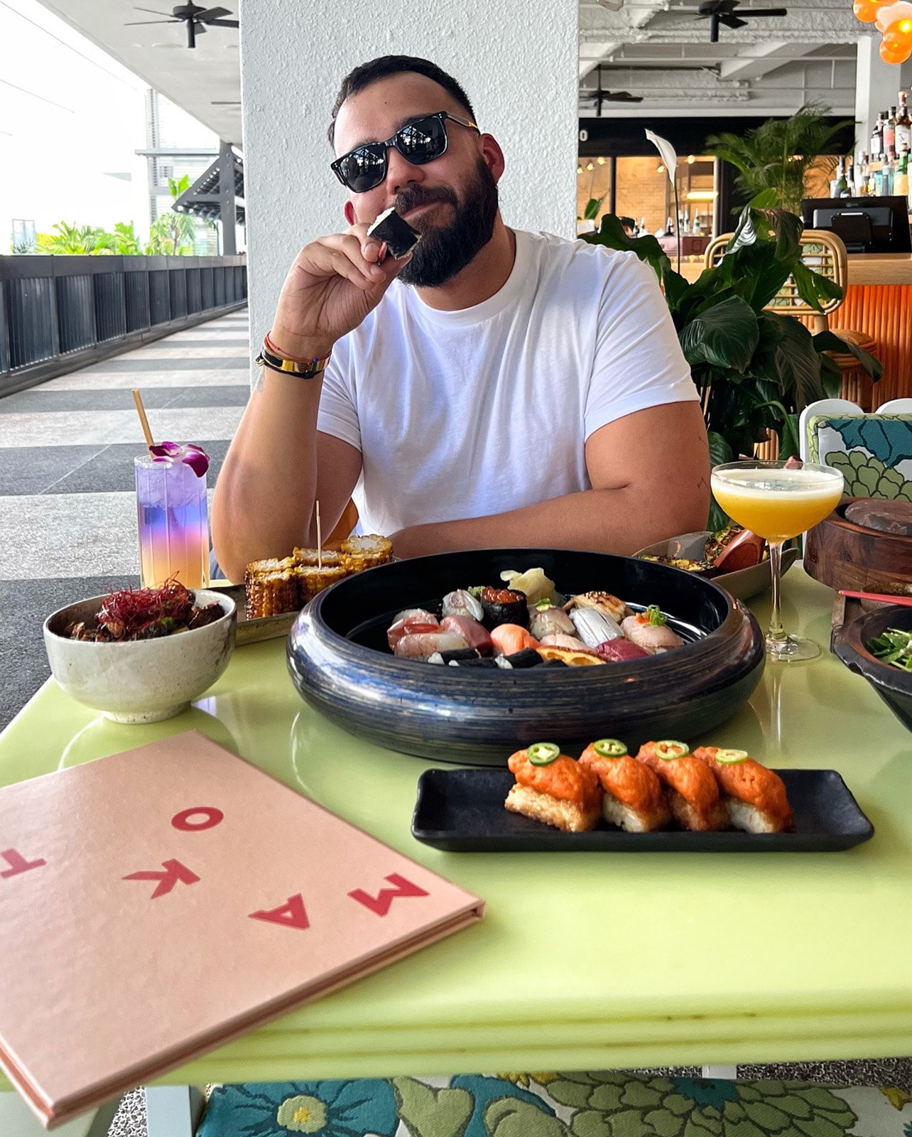 Man smiles while holding up a piece of sushi from Makoto