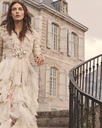 Model wears a white lace dress on the stairs of a castle