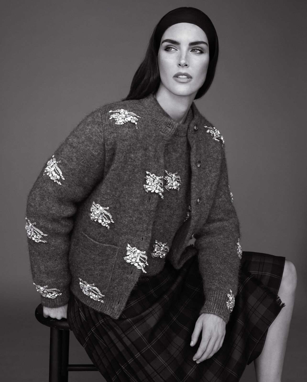 Model poses in a cardigan and plaid skirt