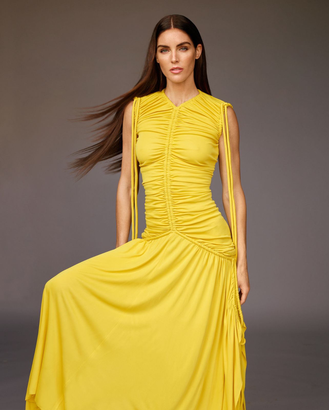 Model poses in a ruched yellow maxi dress