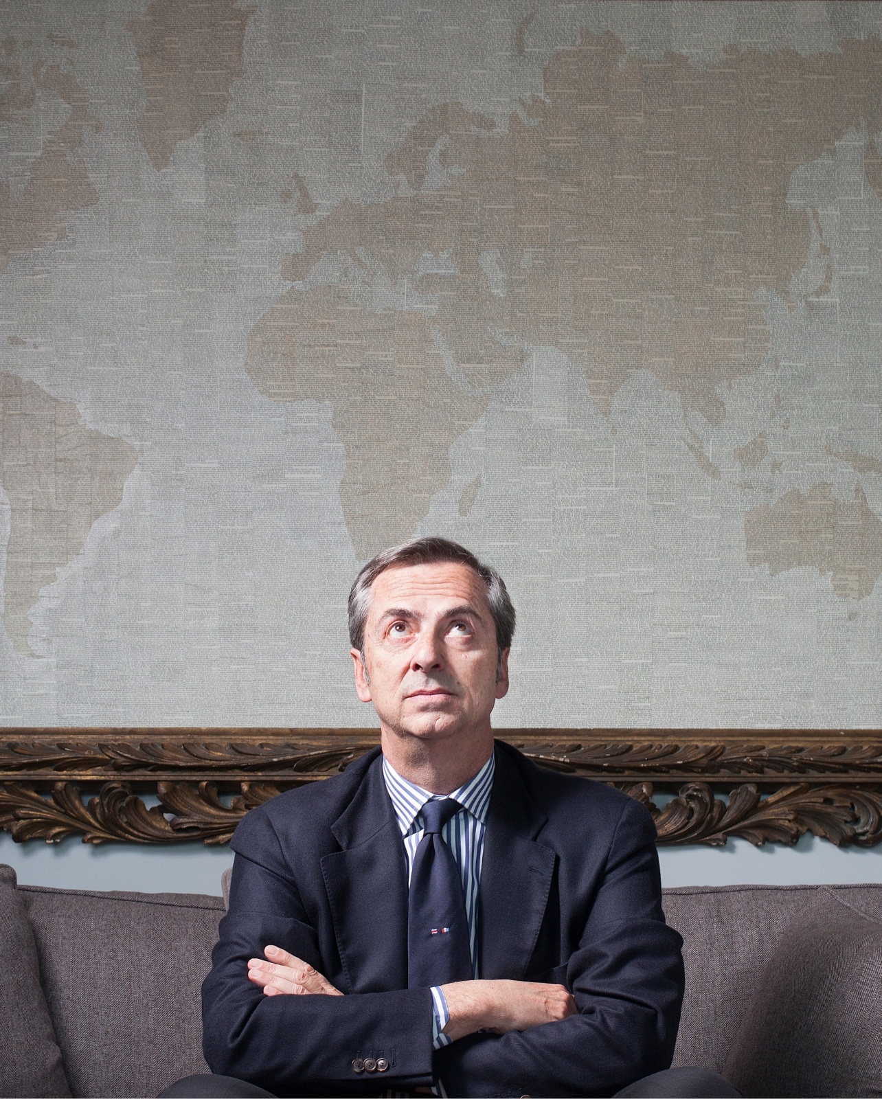 Portrait of president and CEO of Vhernier seated on a couch, looking up with arms crossed
