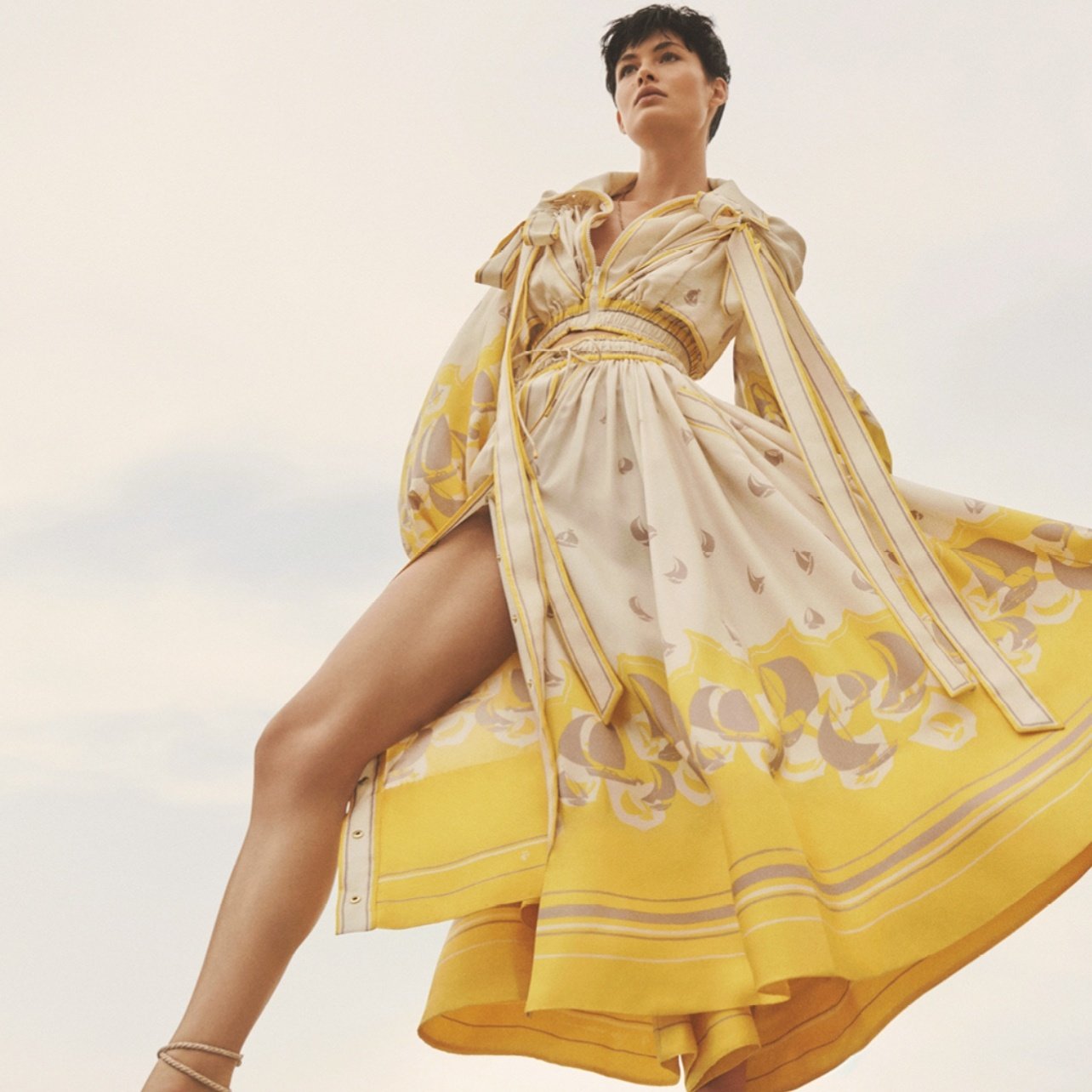 Model dressed in long yellow and tan sailboat print dress