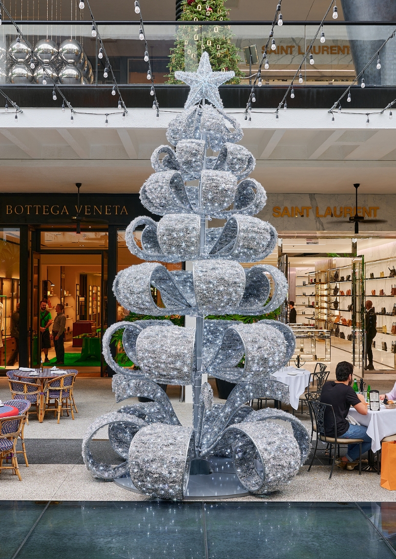 Seven-tiered silver tree with ribbon-like branches illuminated with white lights and topped with a star