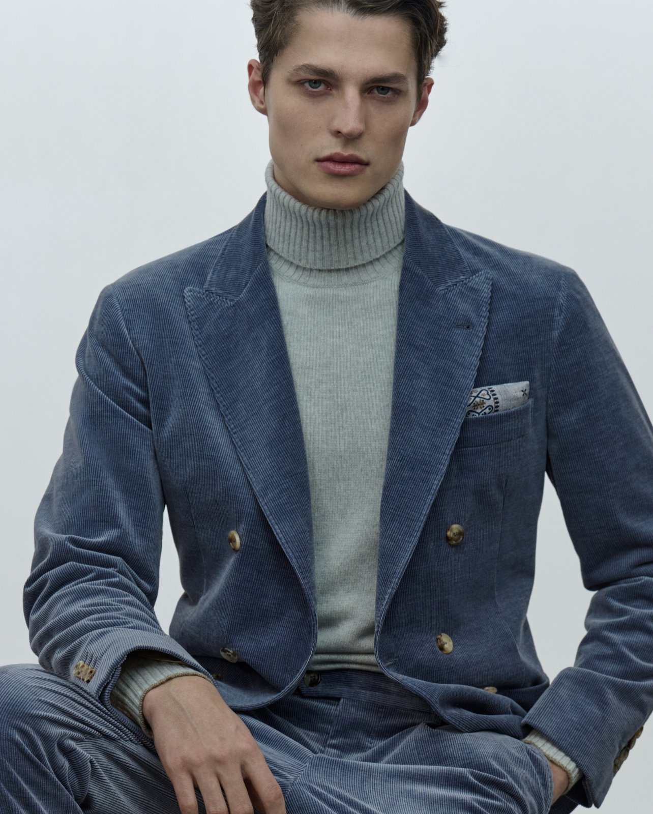 Model dressed in a Brunello Cucinelli blue suit and gray turtleneck