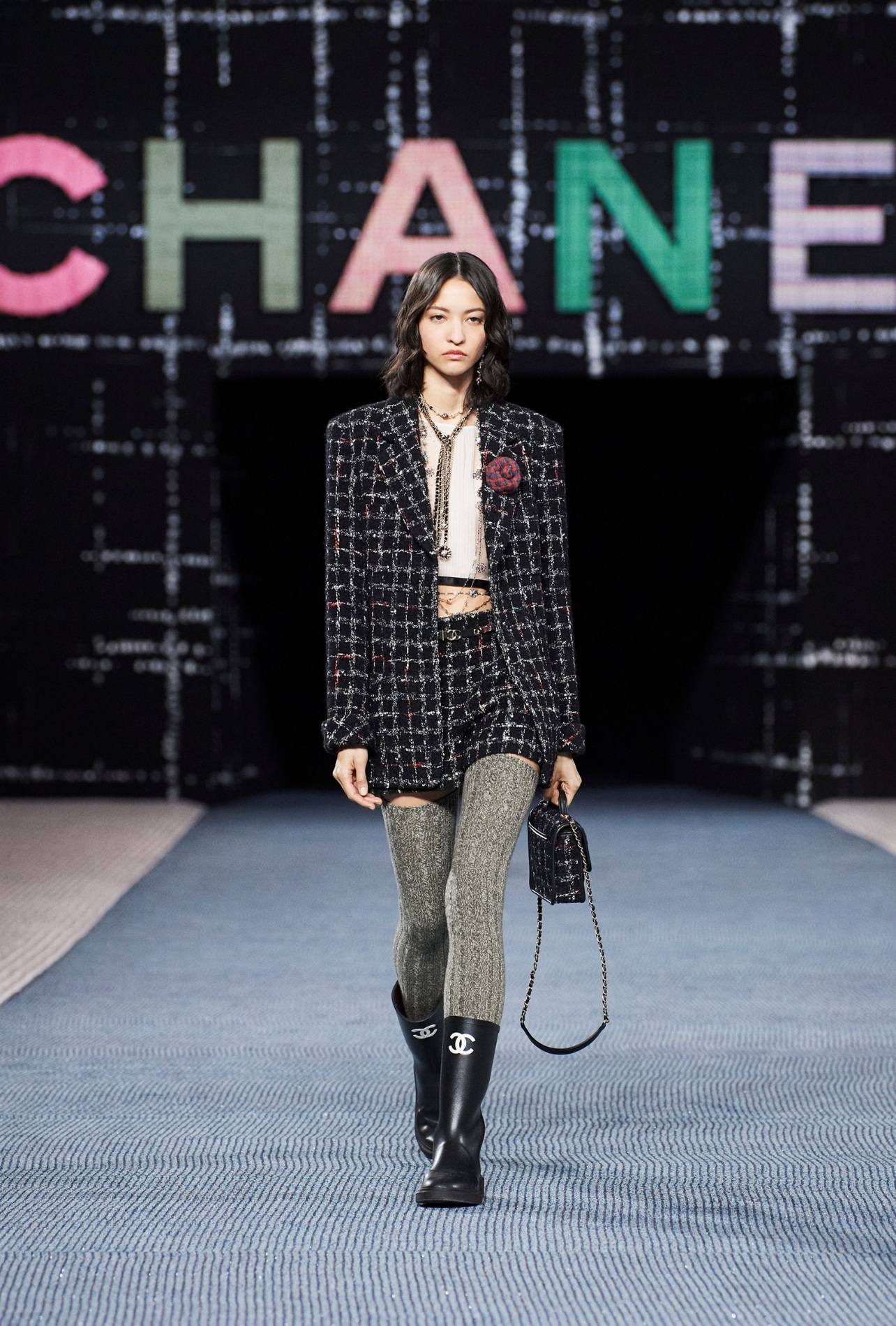 Model in Chanel fashion show wearing rubber boots with interlocking C logo in white