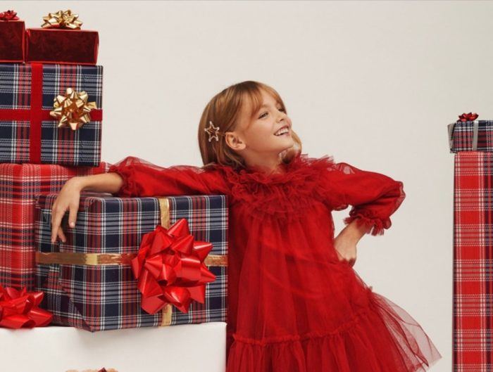 Child model in a red tulle dress with wrapped presents.