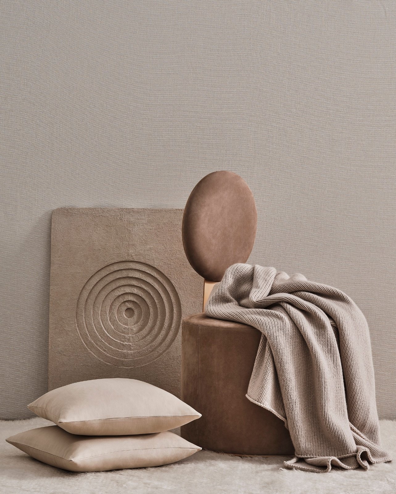 Styled image of tan décor pillows placed next to a velvet brown chair with a tan knit throw blanket