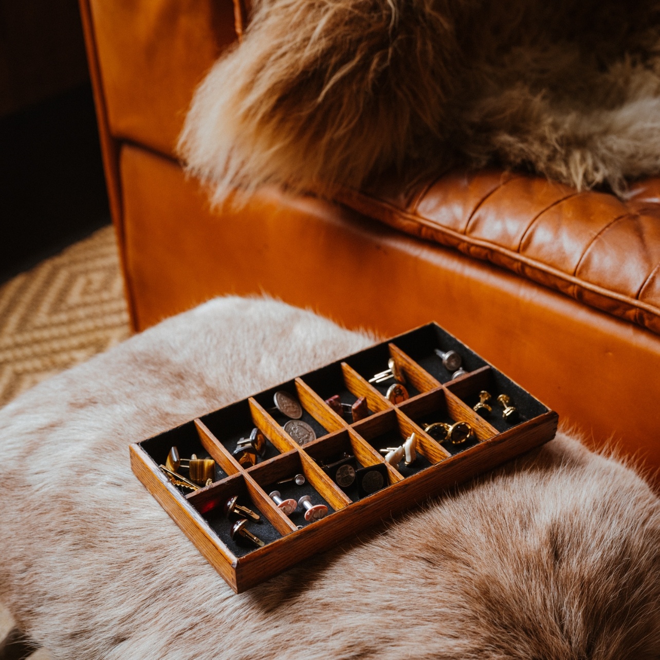 Wooden case filled with an assortment of cufflinks collected by Ken Fulk