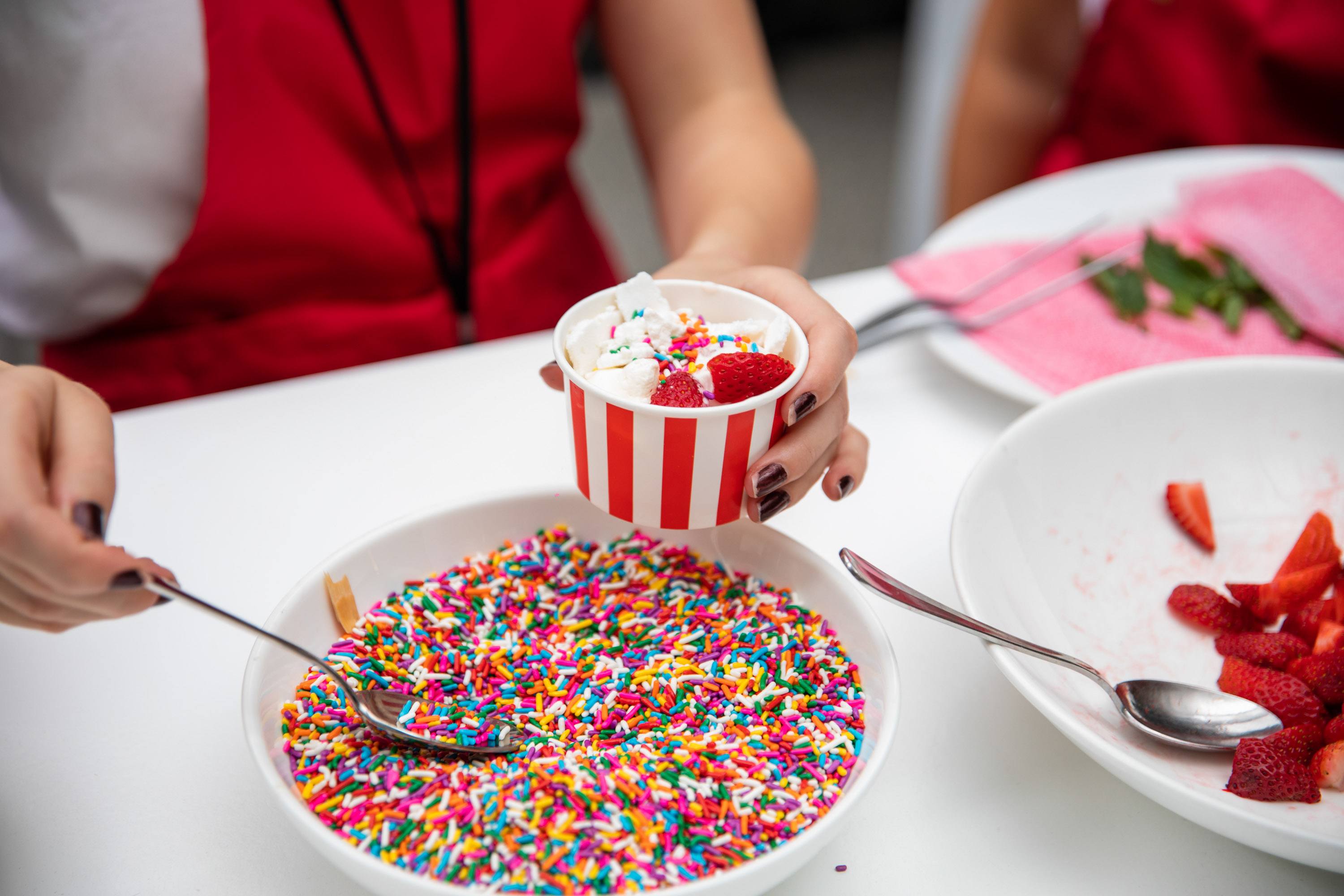 A variety of images showcasing the fourth annual “Ice Cream We Love” event. Images include guests in attendance, ice cream treats and setup, and activities featured at the event including games, face painting, and performances.