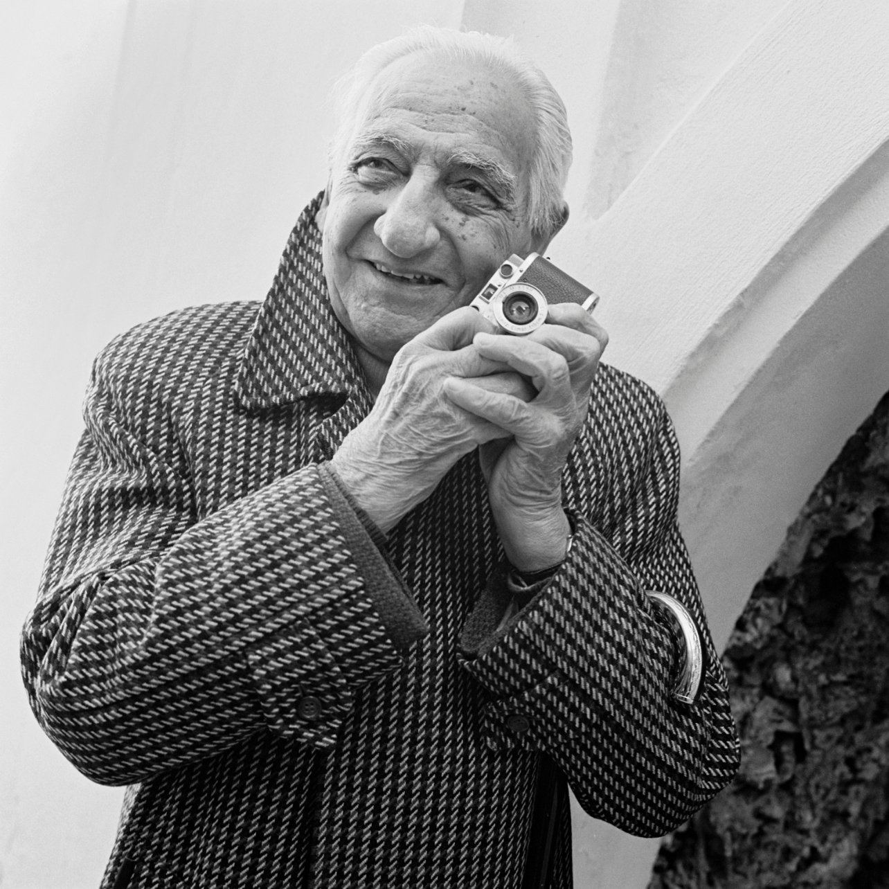 Black and white portrait of Paolo di Paolo holding his Leica camera photographed by Weber