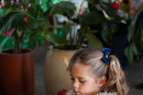Child adding flowers to her clay floral vase