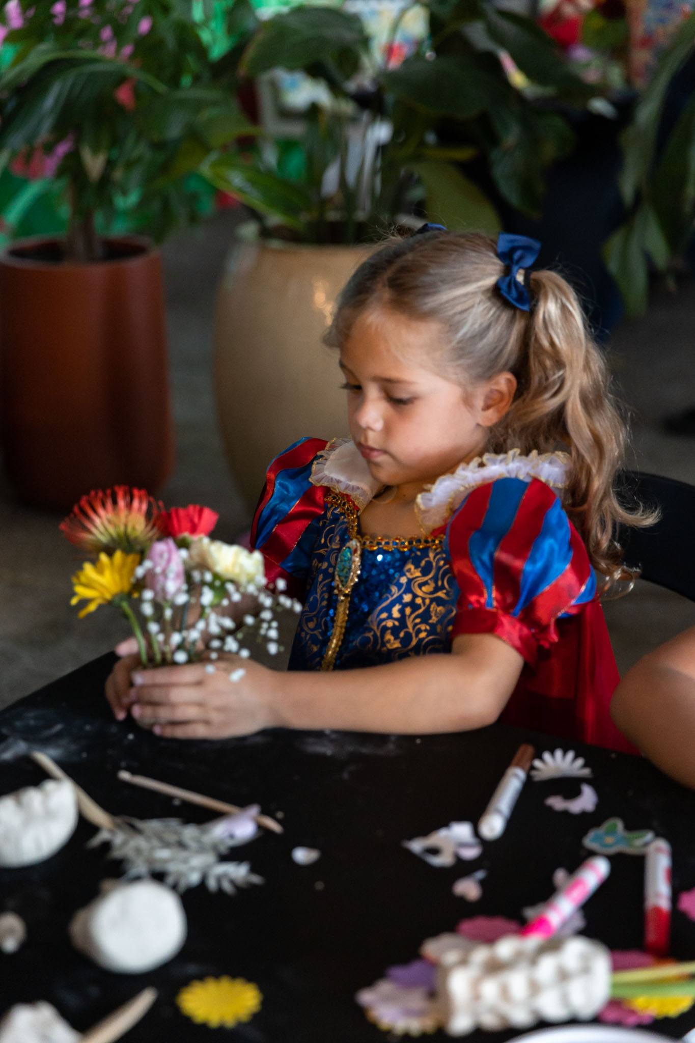Child adding flowers to her clay floral vase