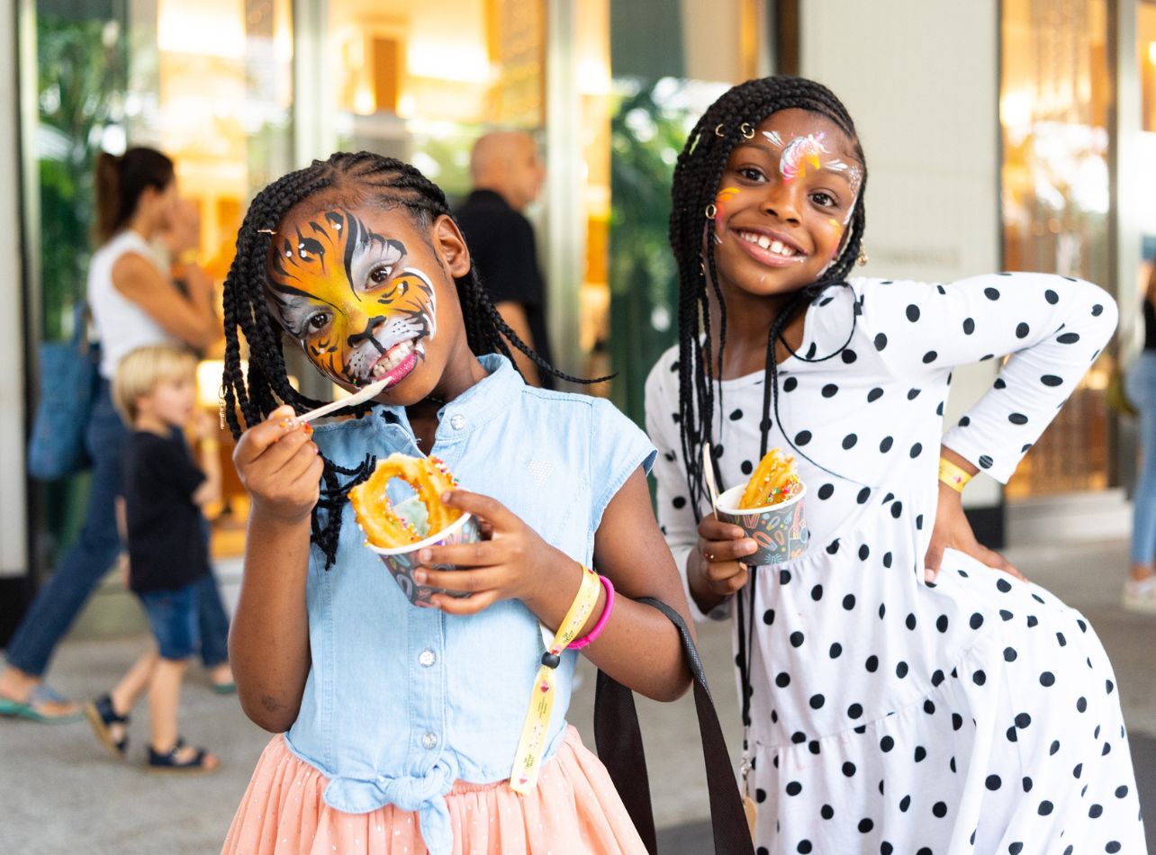 Girls with their faces painted enjoying ice cream with churros