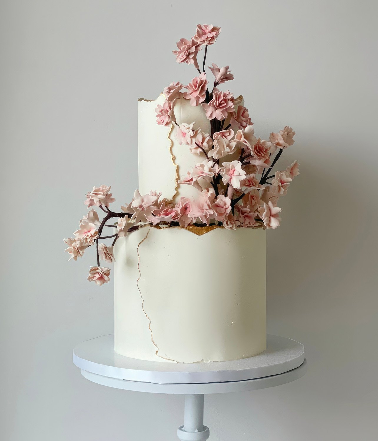 Portrait of a 2-tier buttercream cake with cherry blossom-inspired sugar flowers