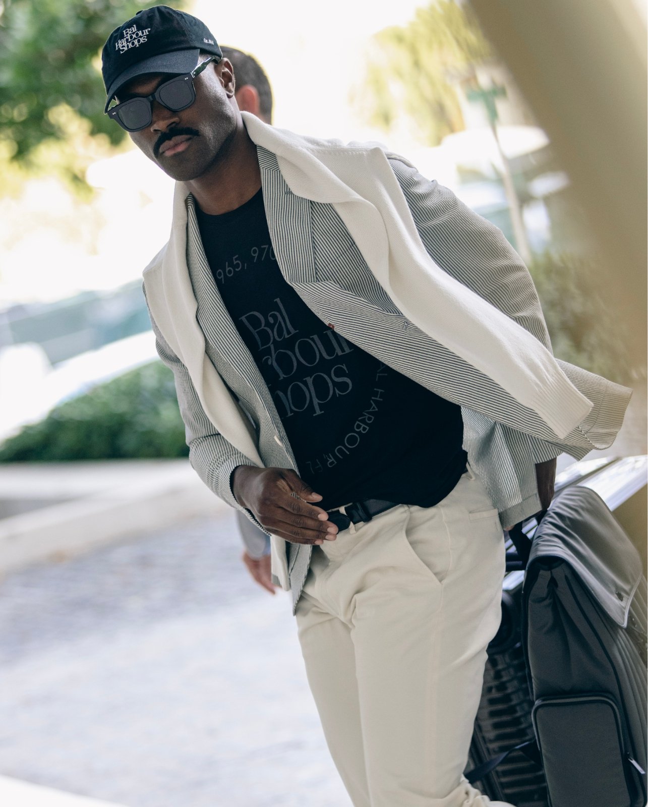 Lifestyle shot of male model styled in the black Bal Harbour Shops 1965 hat and t-shirt with brand logo