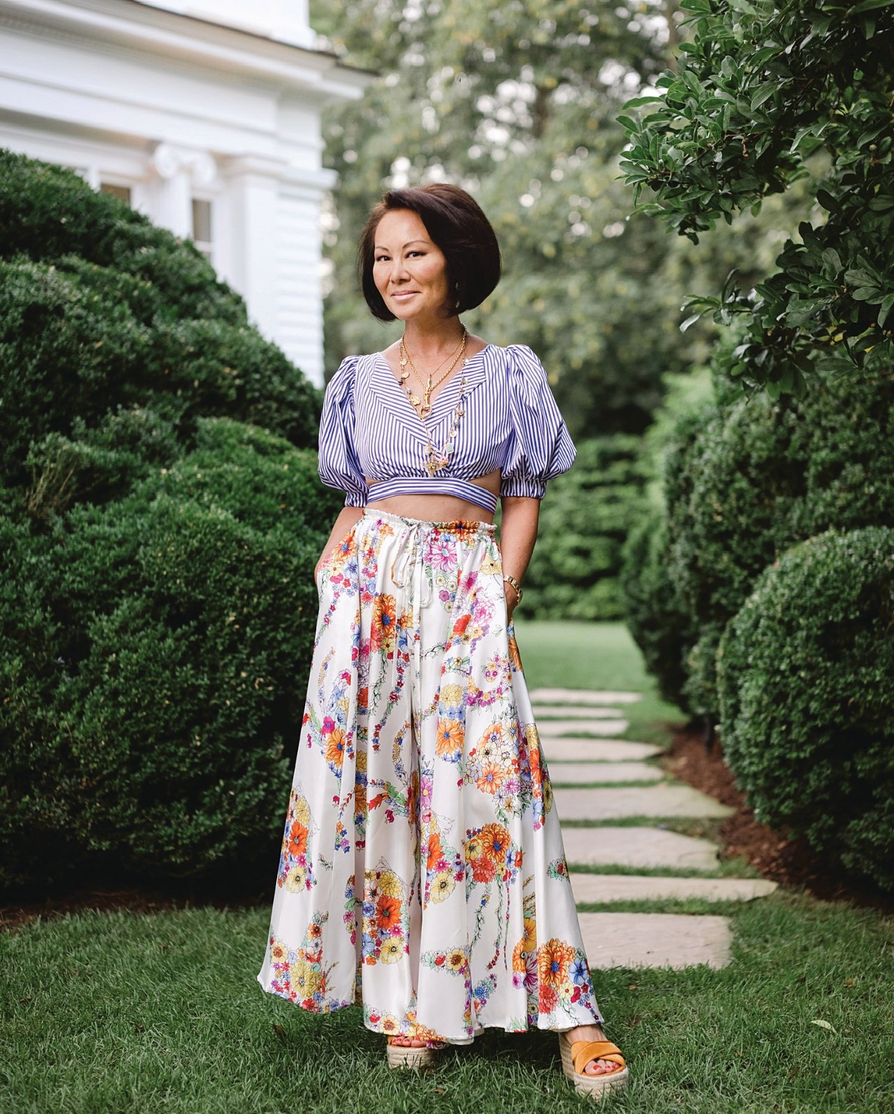 Portrait of Alina Cho wearing a floral print maxi and striped crop blouse