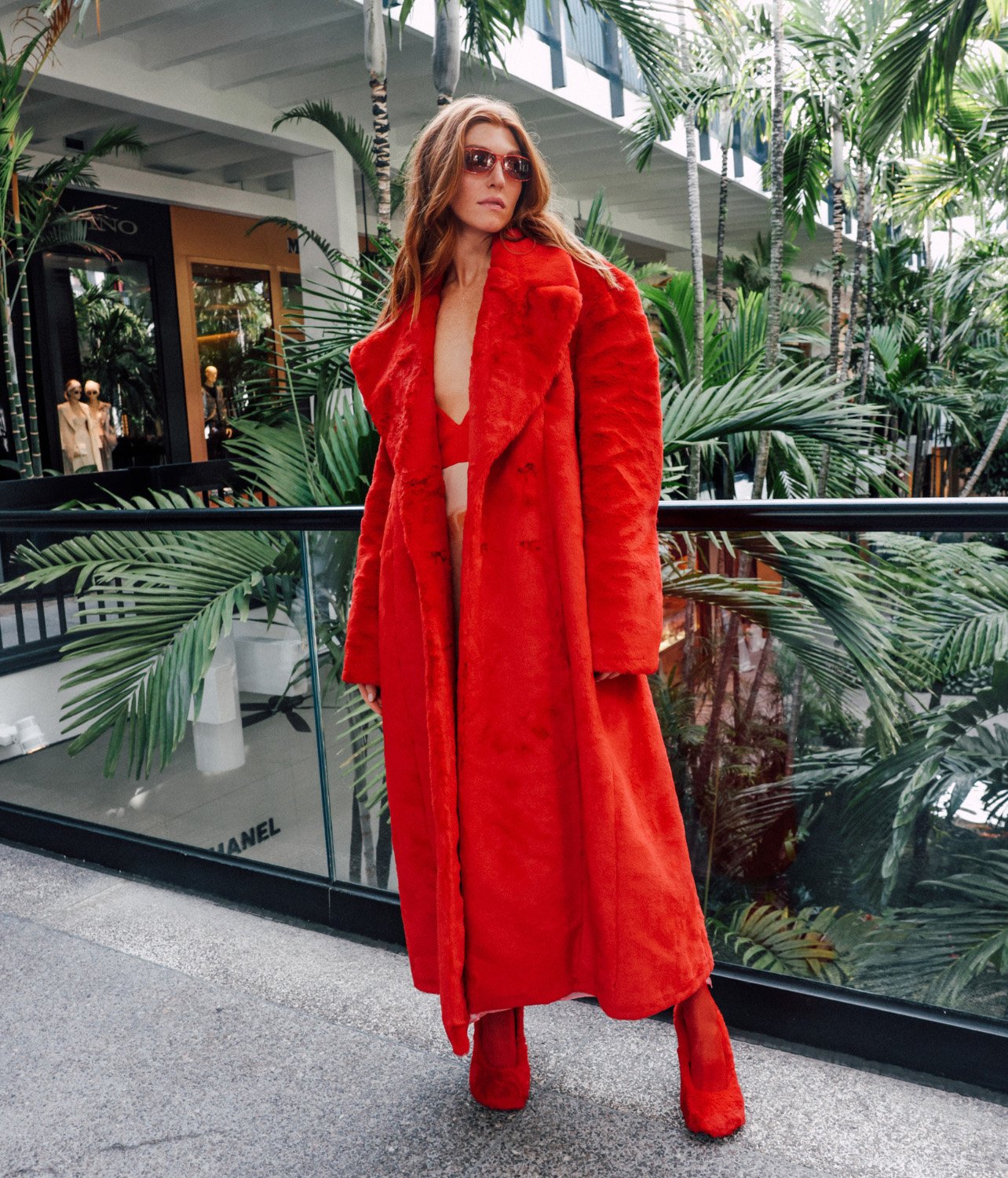Model Kate Krueger wearing a full Stella McCartney look including red fur coat, pumps, and glasses