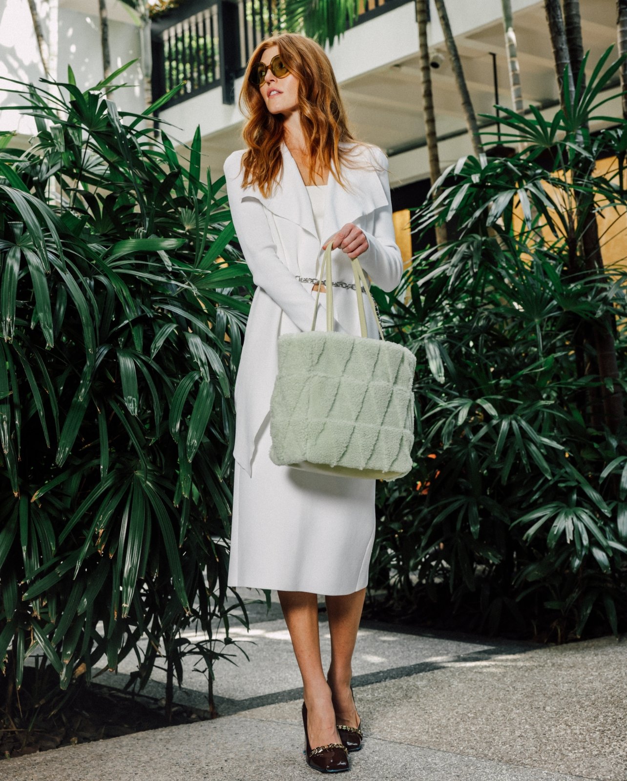 Model Kate Krueger wearing a white Scanlan Theodore outfit with sage sherpa tote bag shot at Bal Harbour Shops