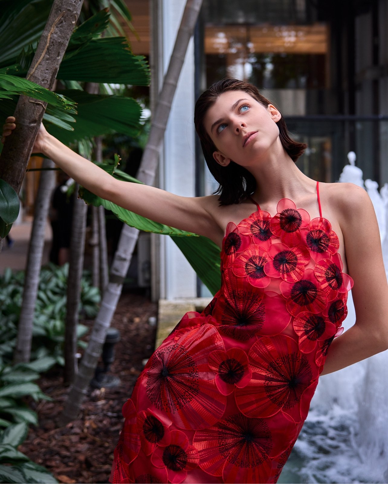 Model posing at Bal Harbour Shops wearing a red mini dress with 3D floral details