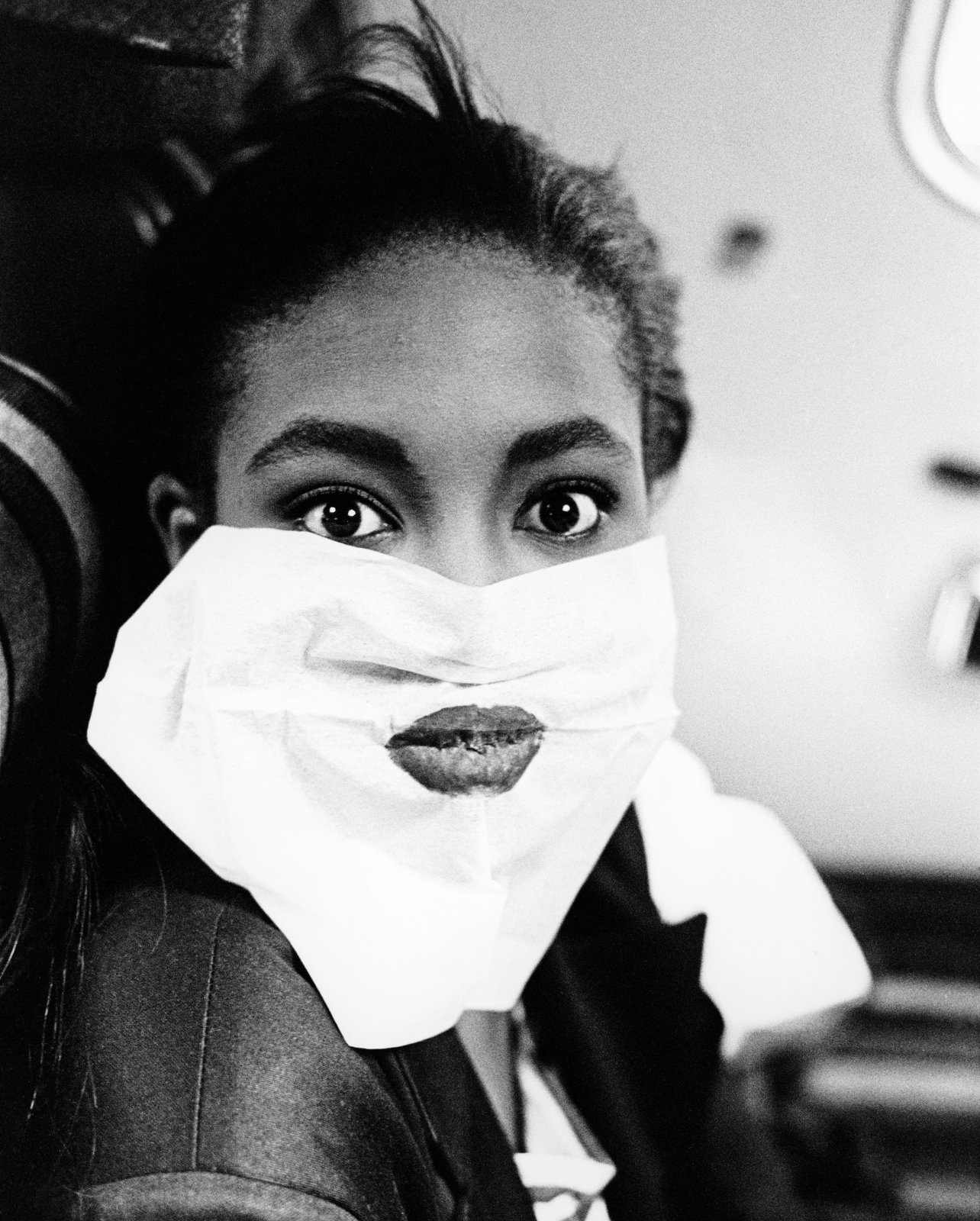 Black and white portrait of Naomi Campell backstage doing her lipstick