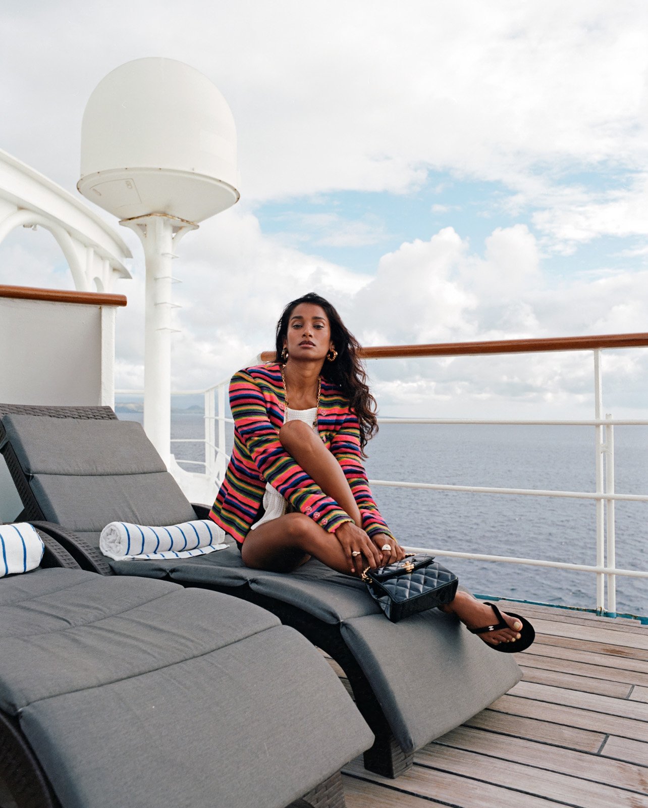 Nidhi Sunil posing in Chanel shorts, jacket, sandals, handbag, necklace, and jewelry