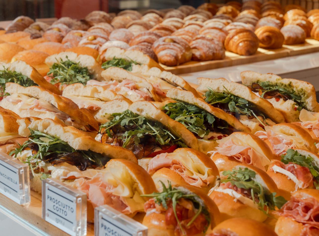 Variety of sandwiches and croissants in glass display case