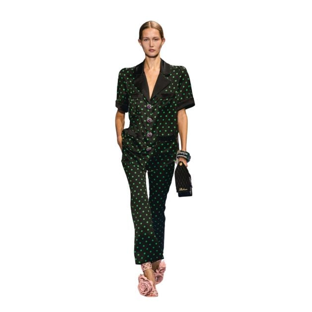 Model wearing black and green polka dot pant and embellished top on runway from Spring/Summer Collection