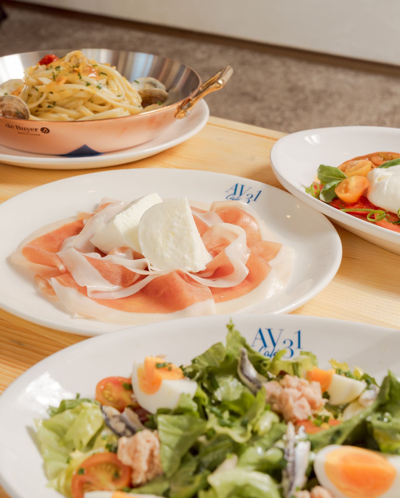 A spread of dishes including Escarole Salad, Linguine Alle Vongole con Clams and Mozzarella with Prosciutto
