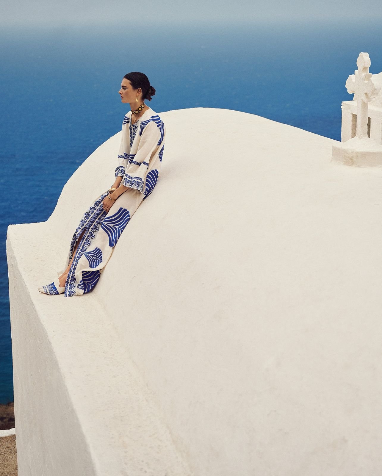 Model on white Roof in Greece with water view in background