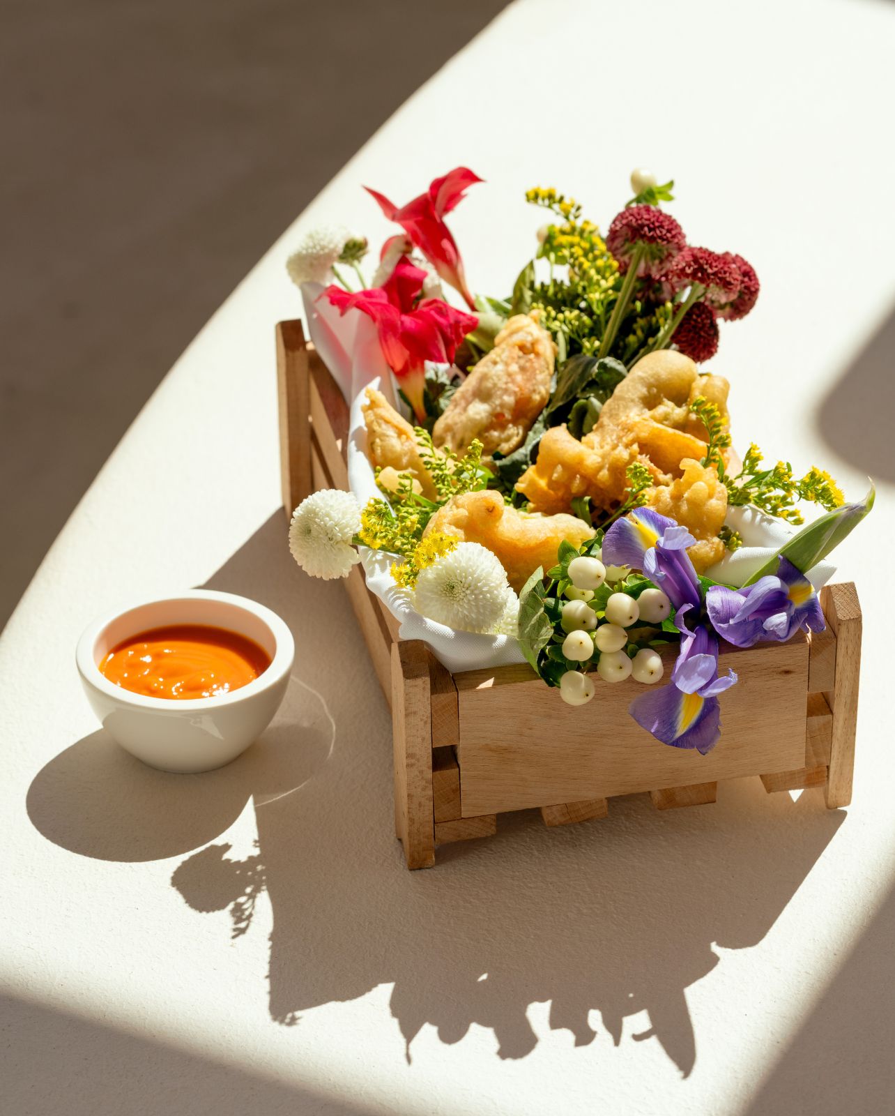 Dish of Tempura plated with floral and an orange dipping sauce