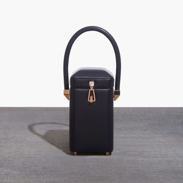 Gabriela Hearst black bag with gold closure on gray backdrop