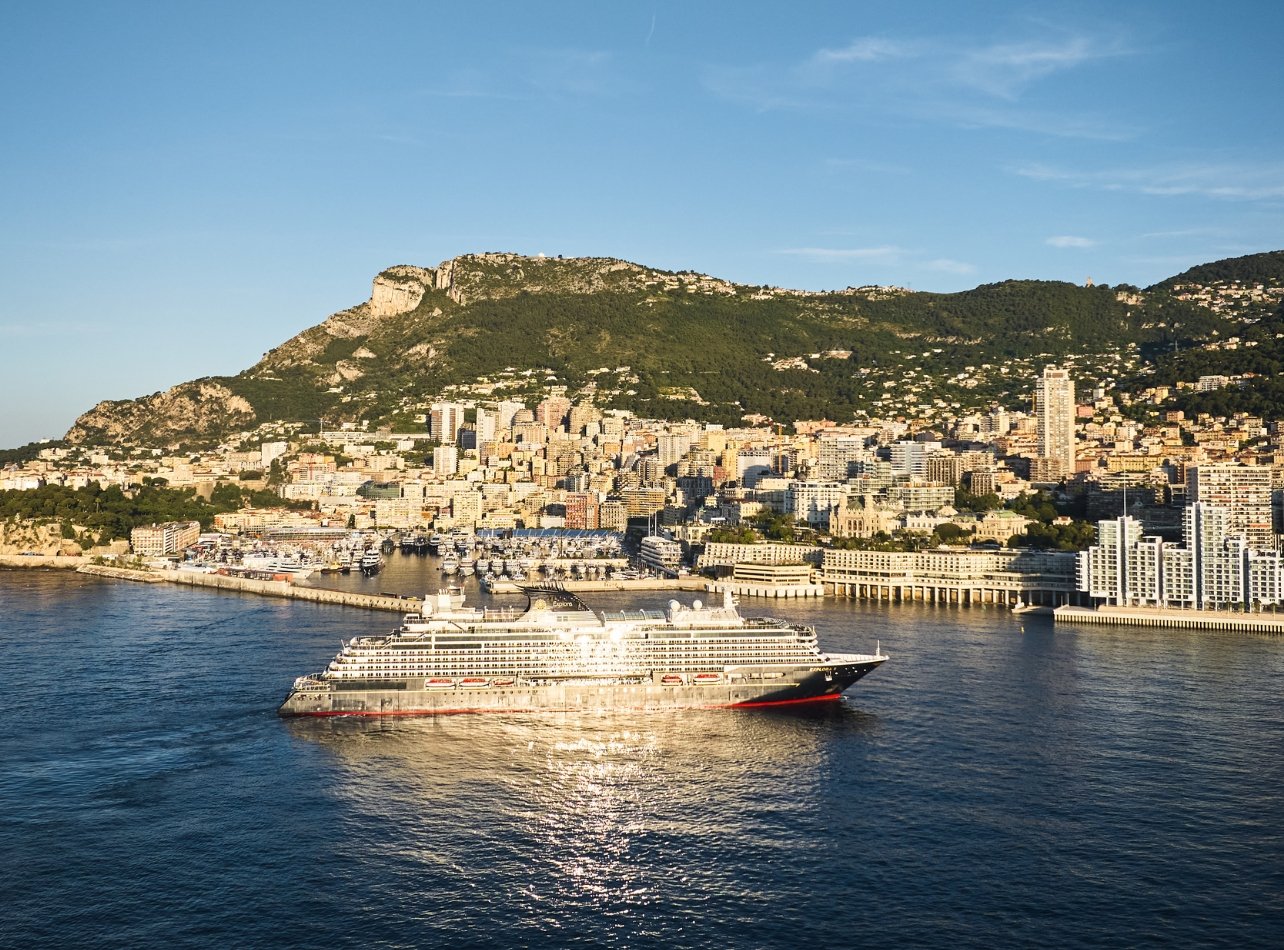 Explora Journeys ship in the middle of ocean with city of monaco in the background