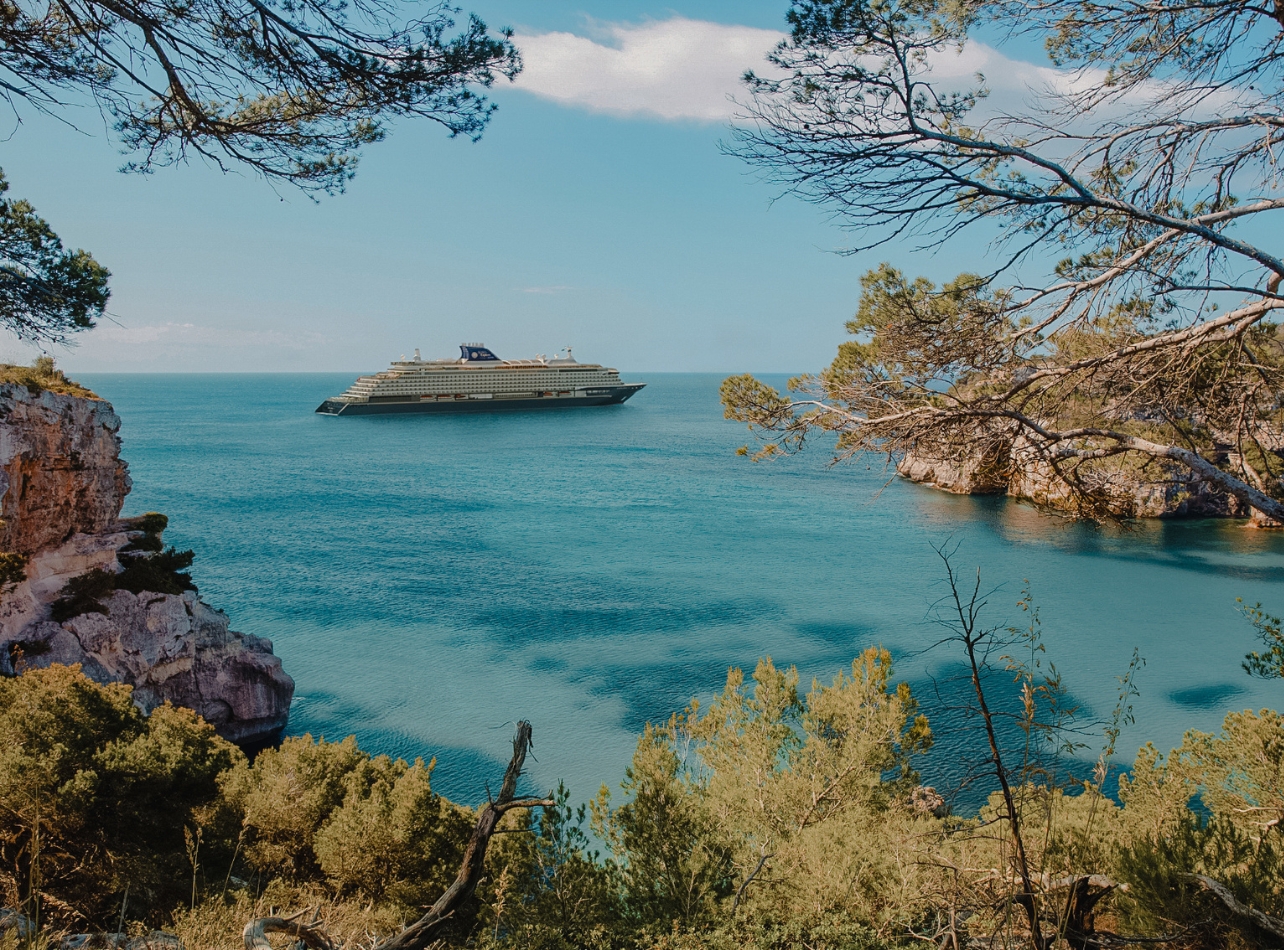 Explora Journeys II ship in the distance on ocean with greenery surrounding