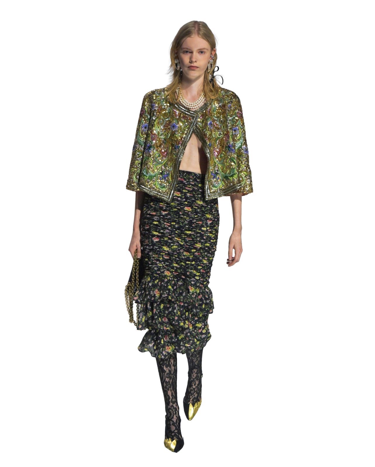 Valentino on model wearing a beaded green jacket, floral skirt, and lace tights