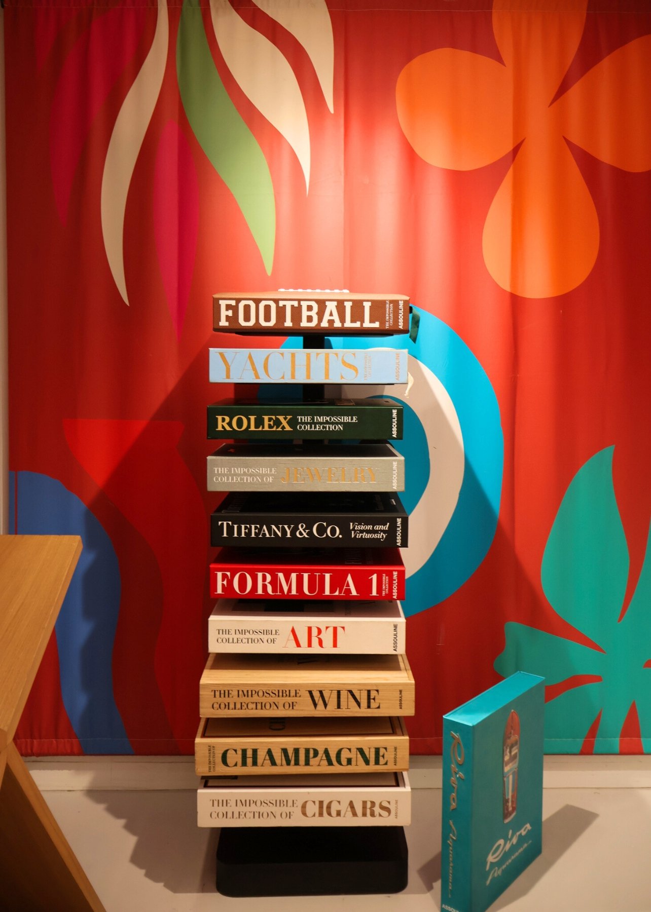 A stack of books on display for the Assouline x Impossible collection at the Bal Harbour Shops Access pop-up event