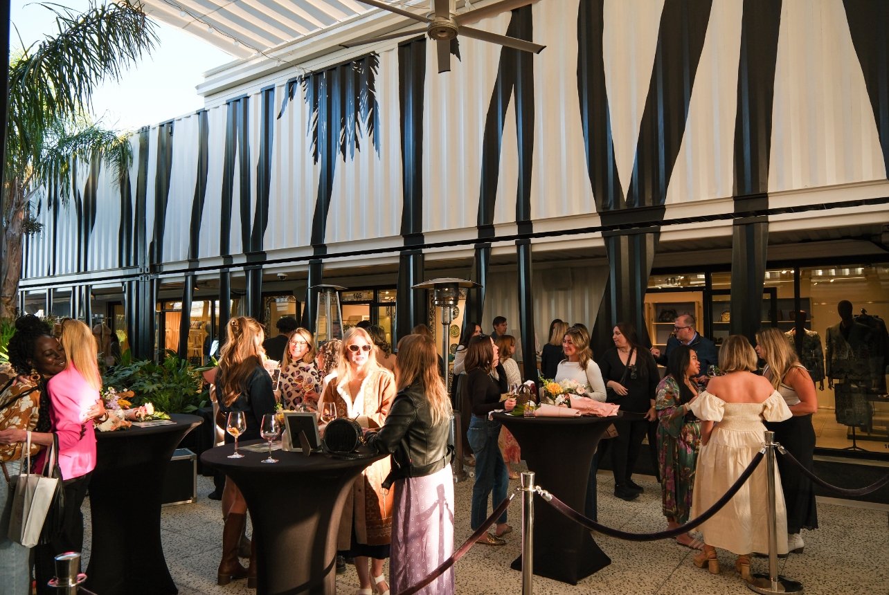 Women socializing in the courtyard with drinks and flour bouquets at a Bal Harbour Shops pop-up event