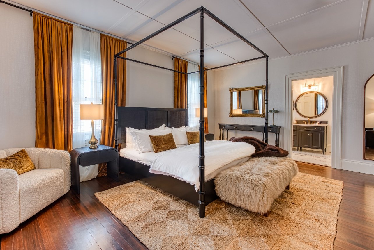 A bedroom in the Doctor Sax House guest room with a canopy bed and fur bench