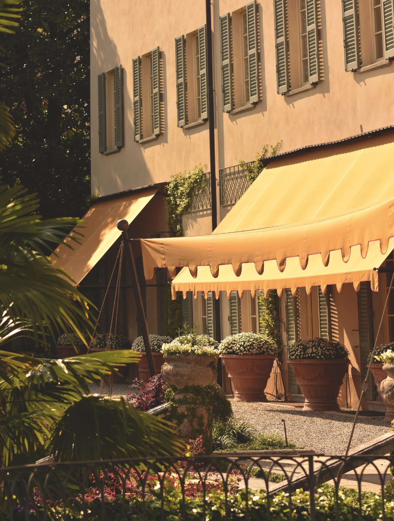 Exterior view of the Passalacqua hotel featuring golden awnings and lush garden landscaping