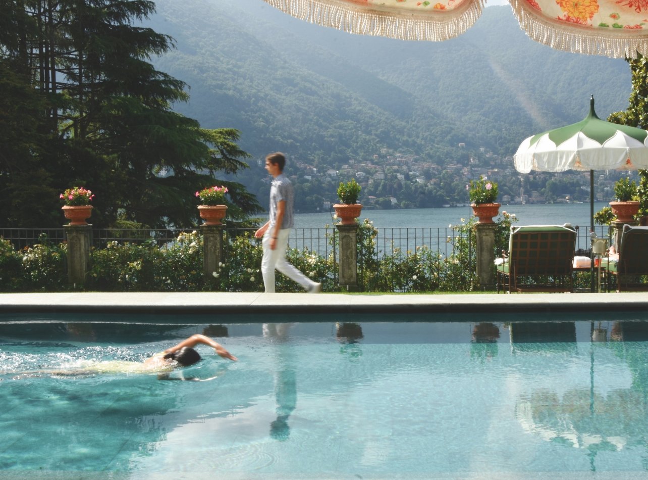 A person swimming in the pool at the Passalacqua hotel, overlooking a scenic view of Lake Como