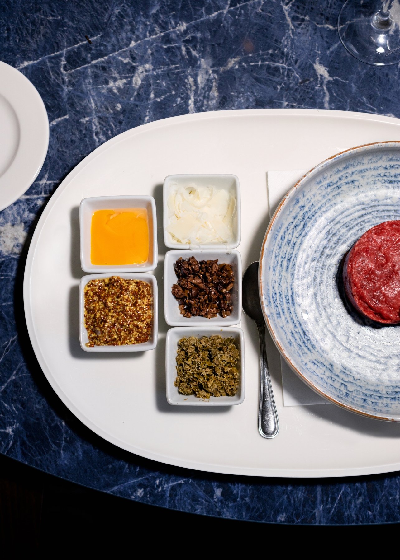 A plate of beef tartare among other small sorted plated dishes