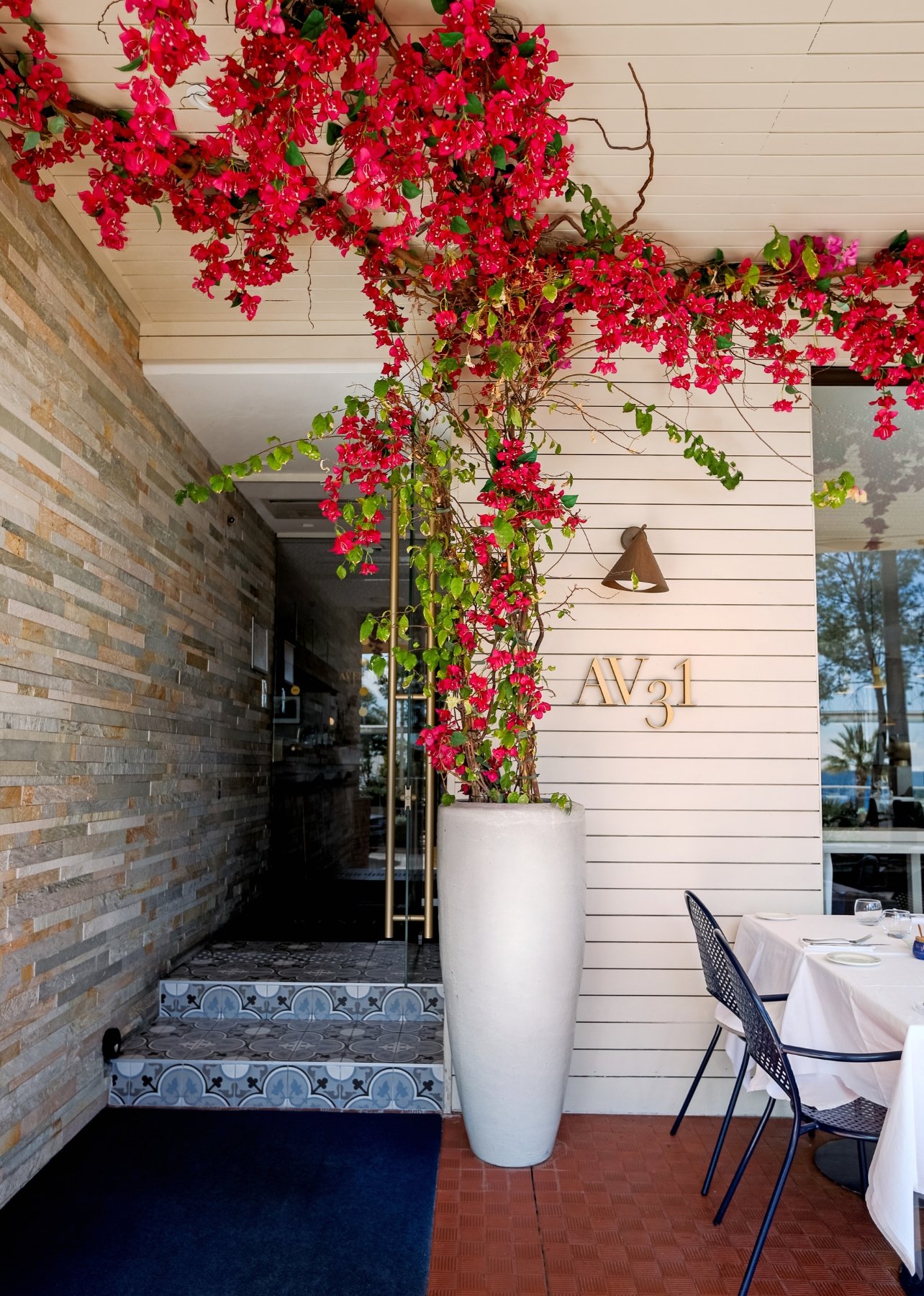 An exterior of Avenue 31 restaurant with a large pink floral arrangement at the entrance