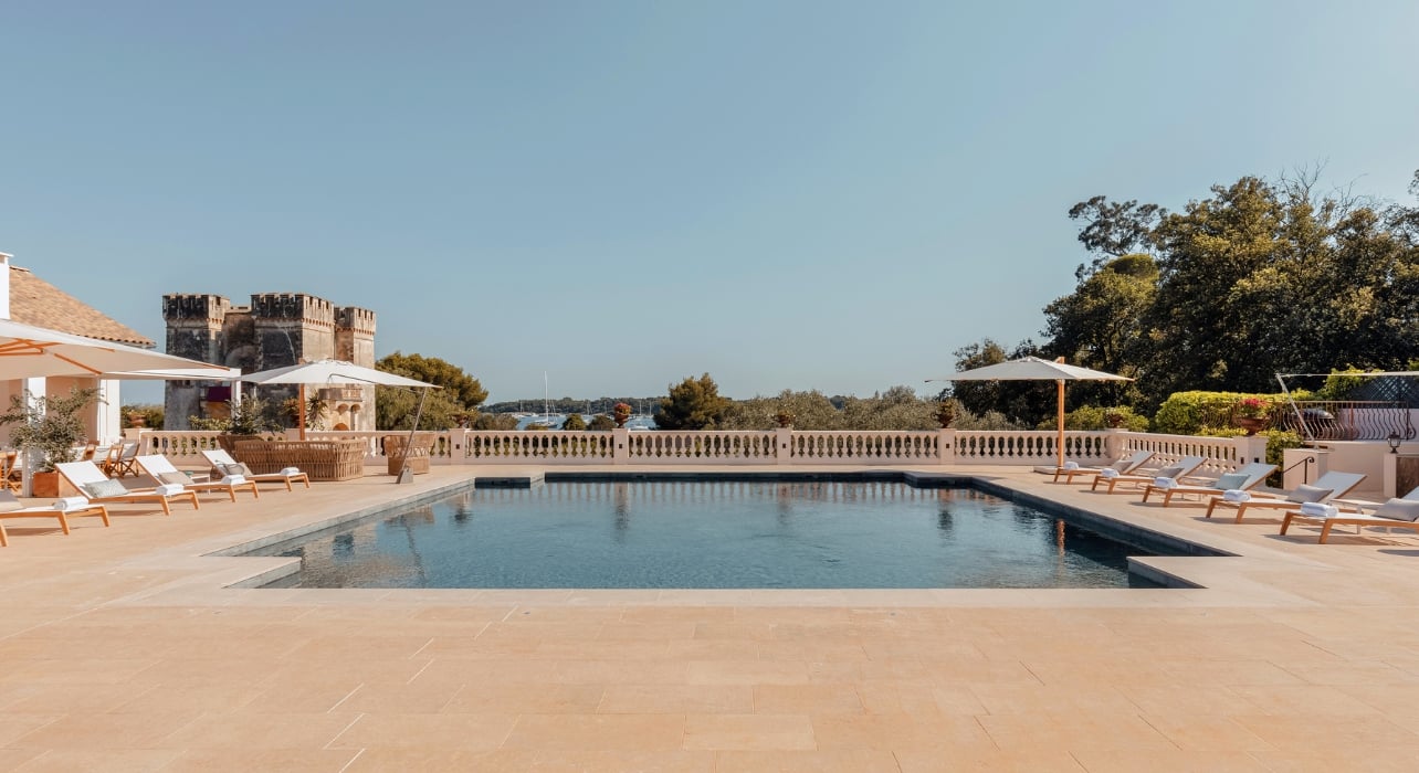 A pool at the Grand Jardin with lounge chairs and umbrellas