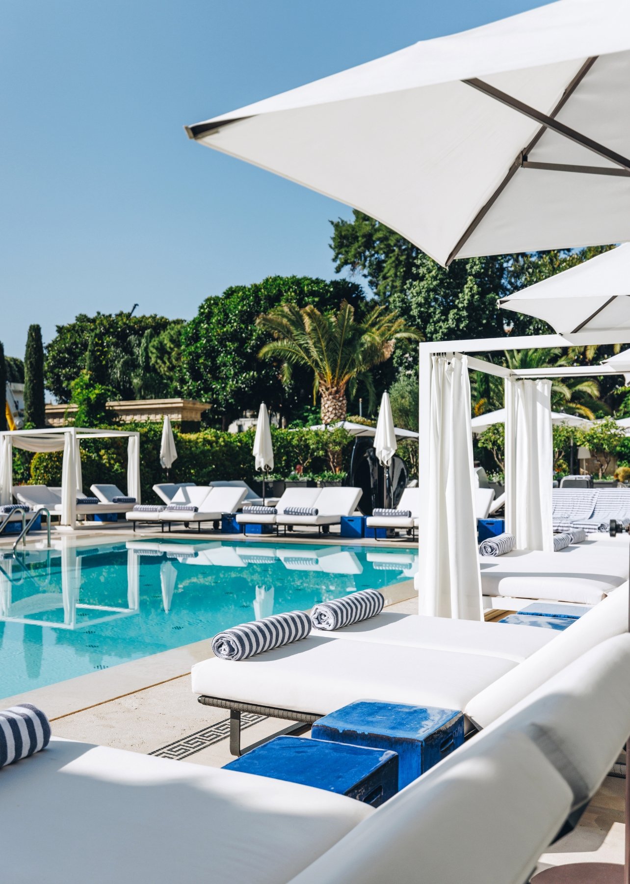 Monte-Carlo’s Hôtel Métropole pool with lawn chairs, umbrellas, and palm trees