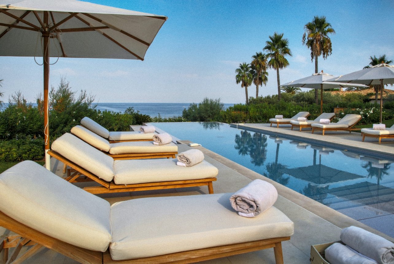 A shot of the infinity pool at the Villa Las Brisas with white lounge chairs and umbrellas
