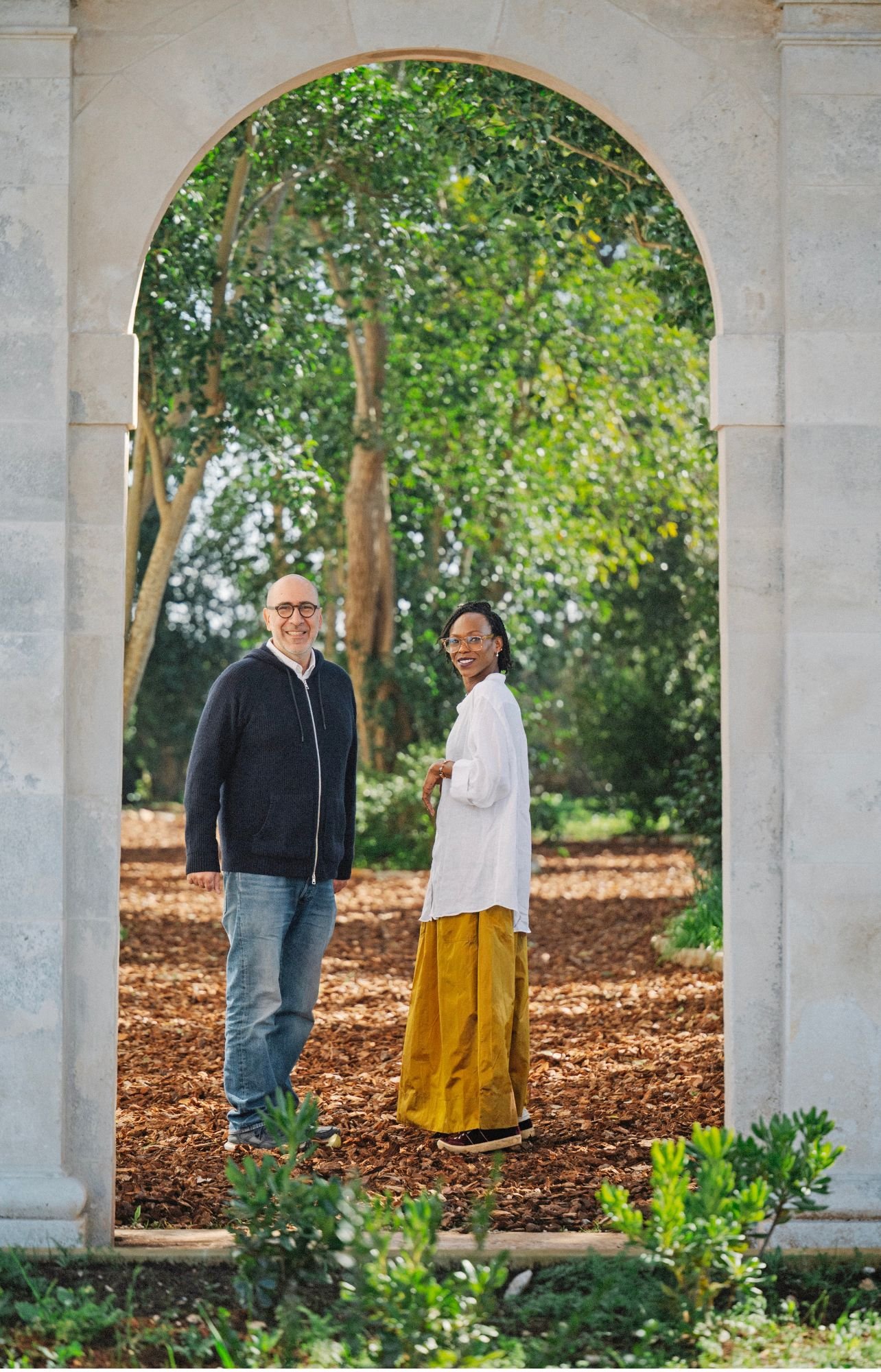 Thelma West and Stefano Liotta standing under a cement arch at Casina Cinquepozzi in Puglia