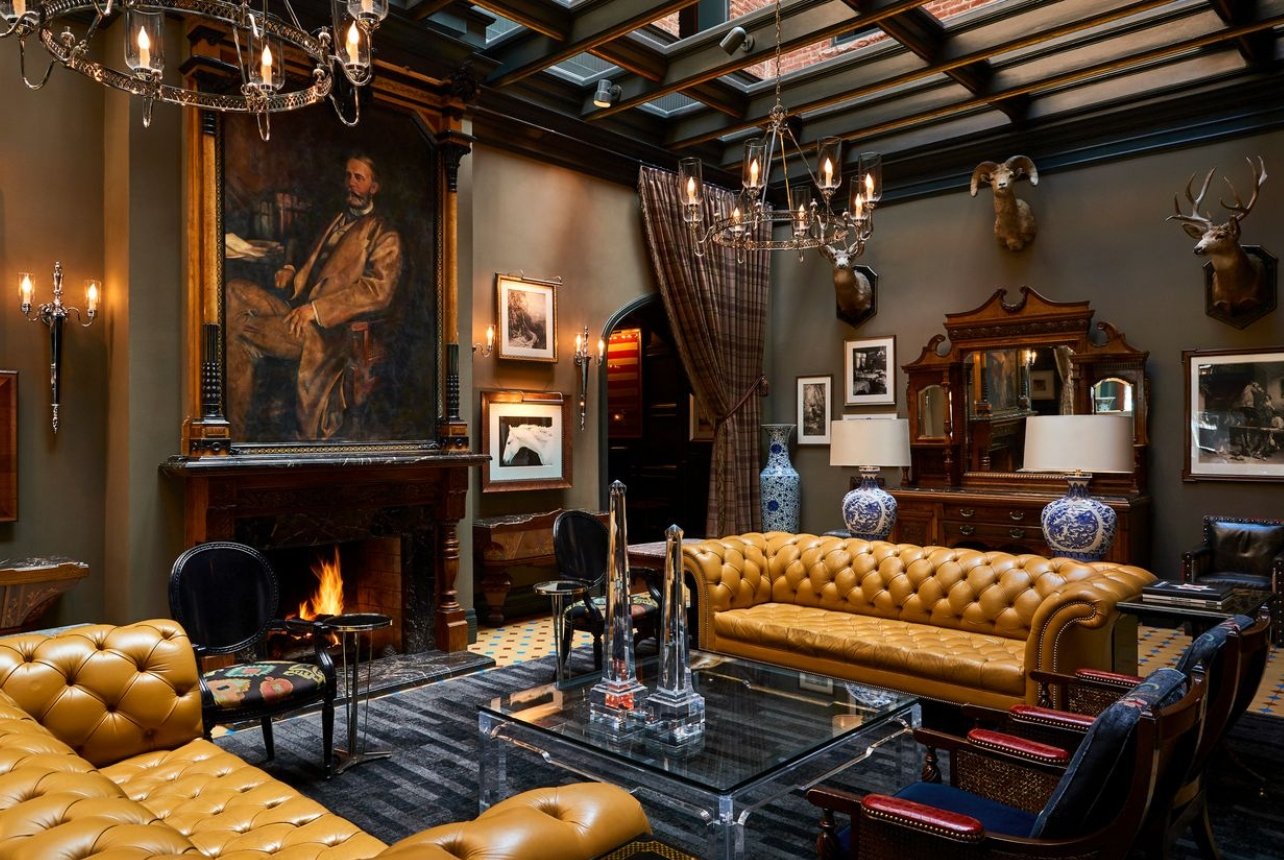 Interior of Hotel Jerome’s grand communal living room with leather couches and a fireplace in Aspen